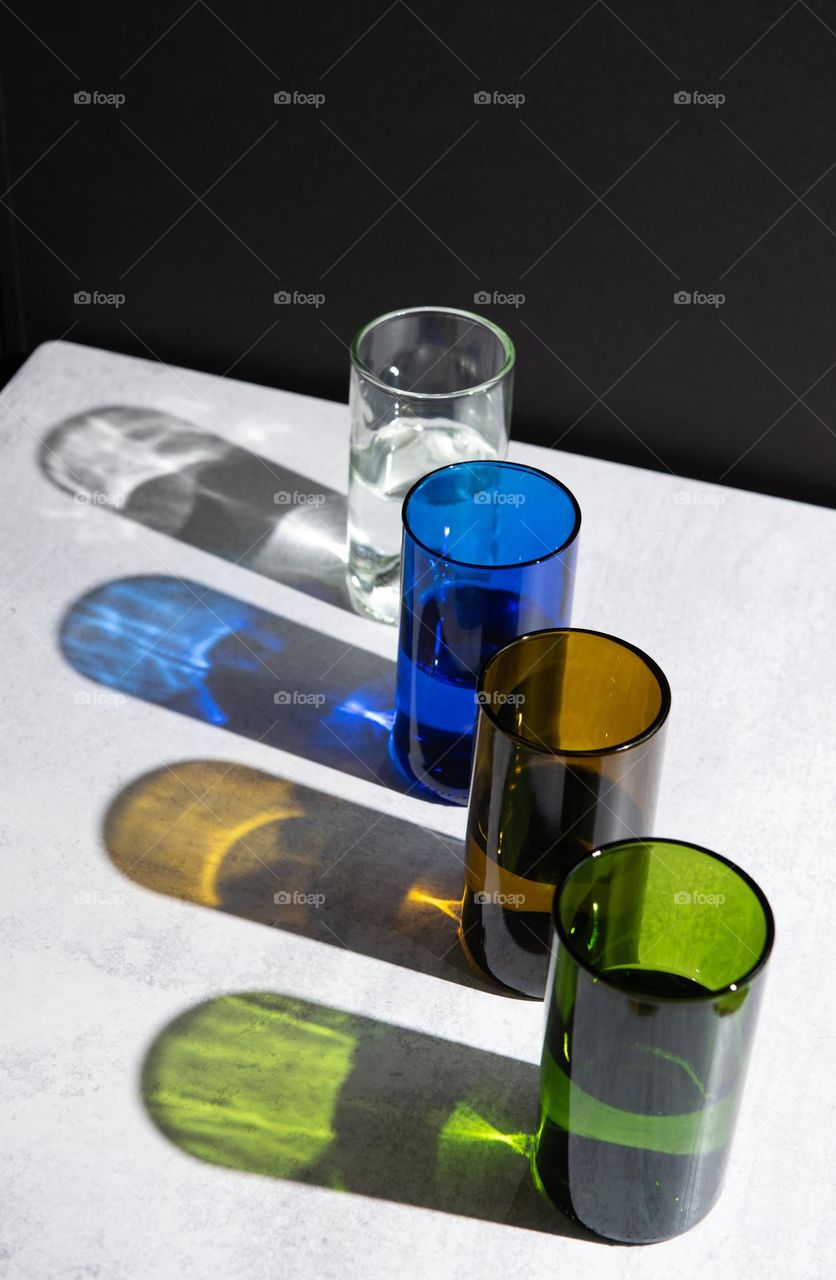 Row of glasses in assorted colors with hard light reflections 