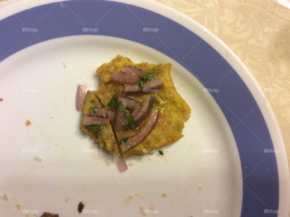 Tostones made from plantain, served as appetizer with onions 