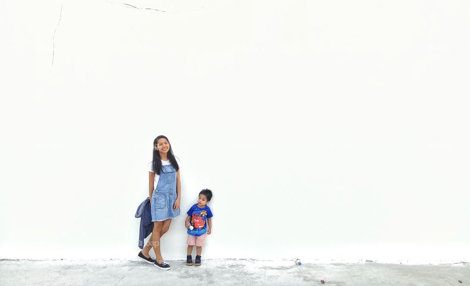 Posing asian little boy and girl in front of white wall