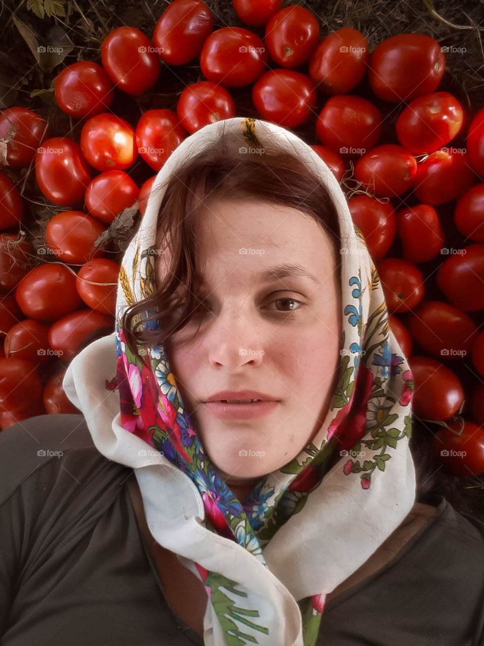 An original portrait of a housewife in an embroidered scarf, among a crop of tomatoes