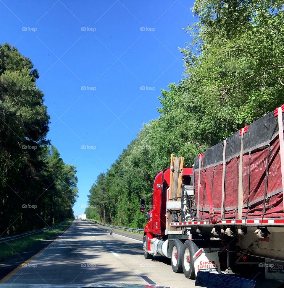 Beautiful view of big red rig as we pass on  highway during roadtrip.