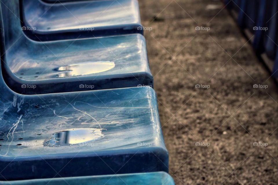 Close-up of puddles in row of seats on blue seats