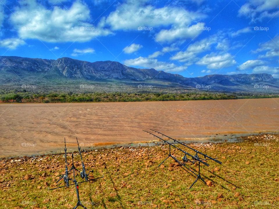 Fishing spot on a blue sky day with some clouds and dirty water