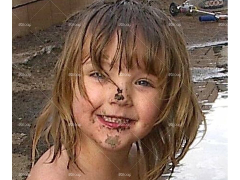 Little girl playing in mud. Cute.