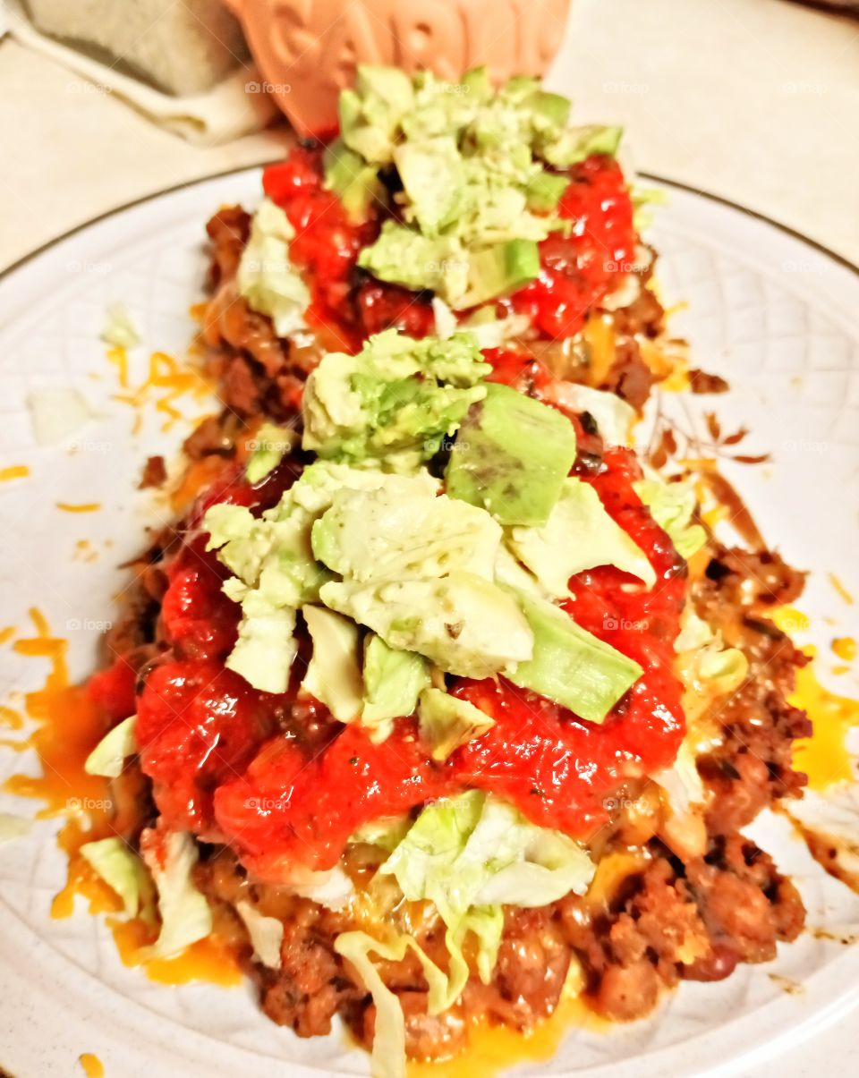 Loaded Tostadas, lightly toasted crispy corn tortilla shells, slowly cook till tender pinto beans, ground pork and ground turkey, top with cheddar cheese, lettuce, hot sauce and Hass avocados.