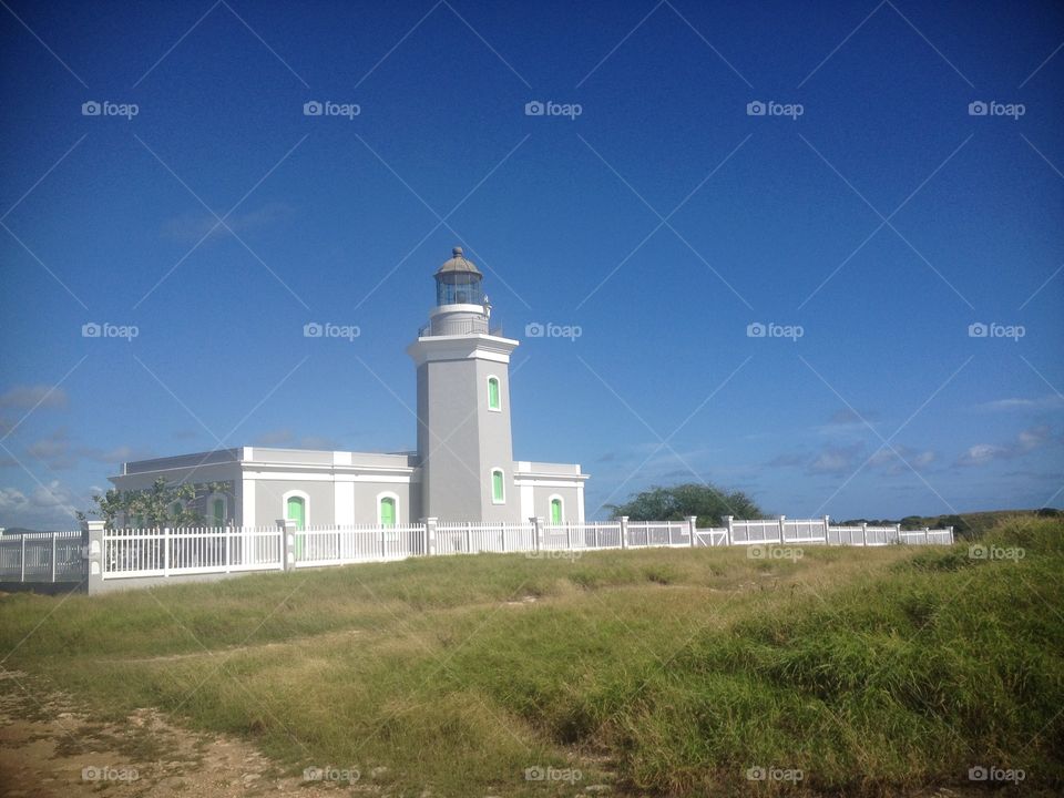 Puerto Rican lighthouse before the hurricane with blue sky and grass