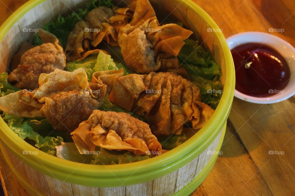 Asian dumplings fried in a bamboo basket with sauce