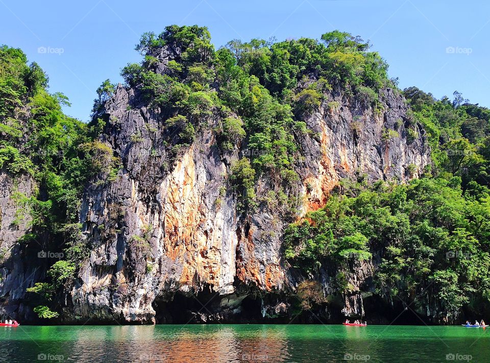 Enjoying the last summer days swimming in boats along the tropical rock 