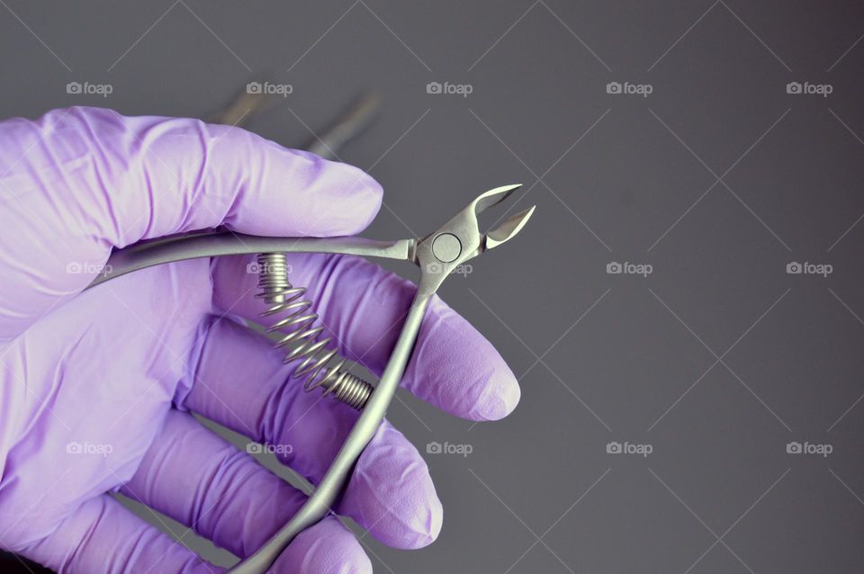 Manicure tools are held by a manicurist in rubber gloves