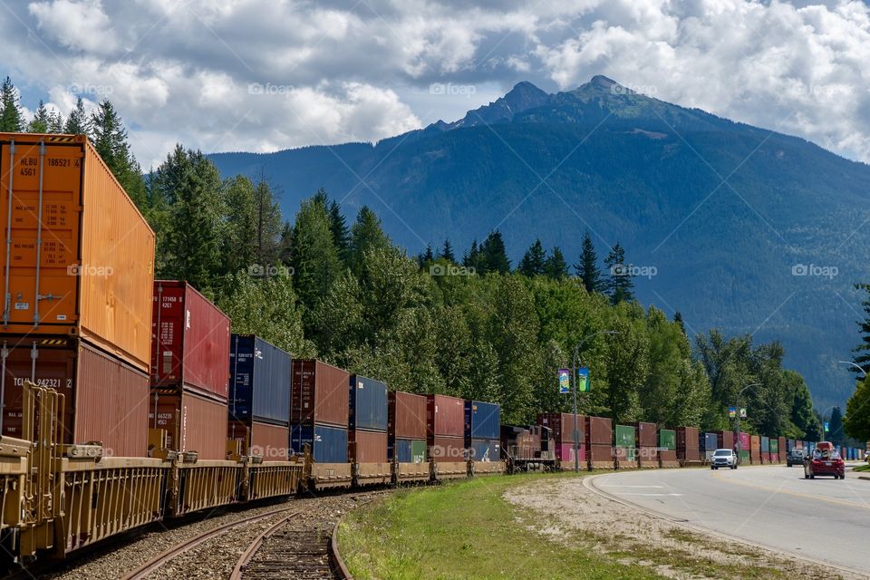 Rail box cars roll down the tracks in mountain setting 