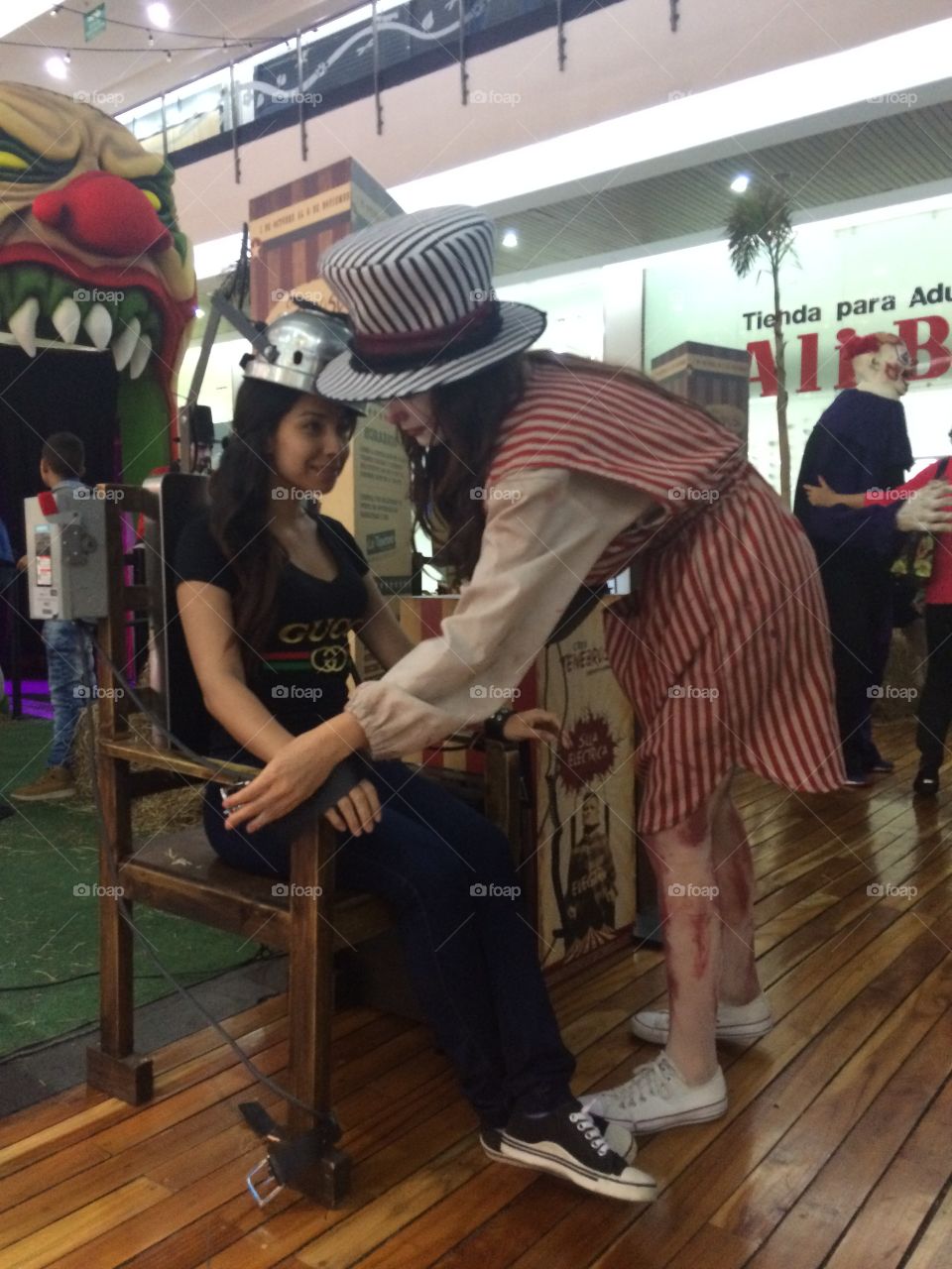 Girl in an amusement park tied to an electric chair and by a crazy hat custom to generate terror 