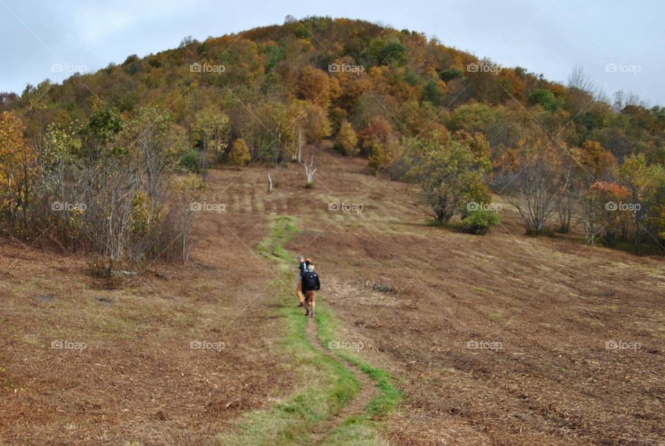 People walking on a hiking trail to a mountain in autumn 