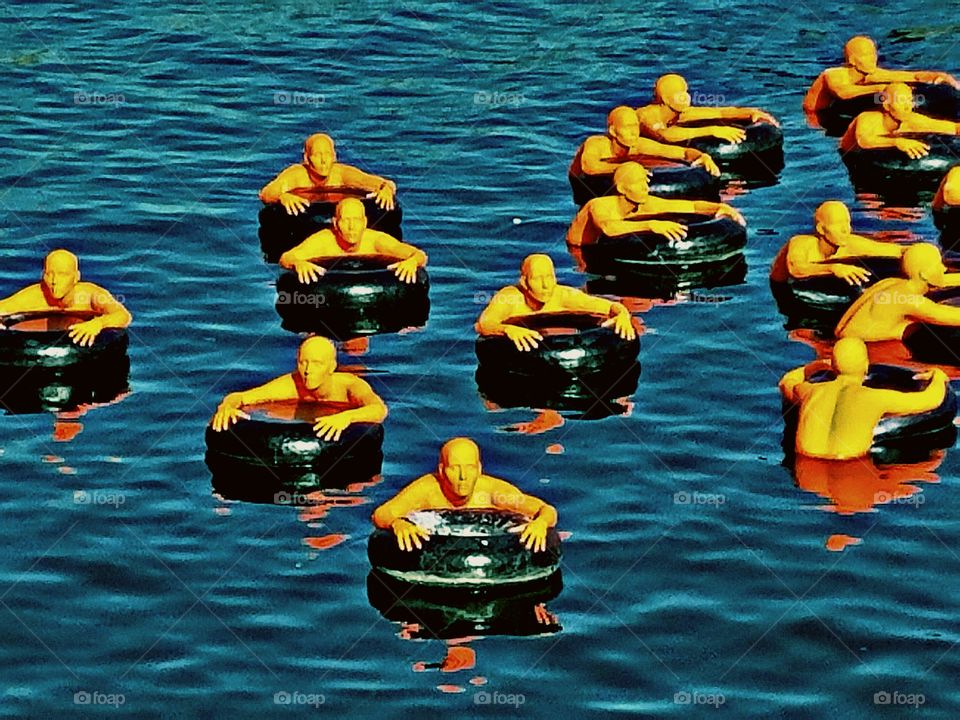 aquatic art installation, orange refugees floating on inner tubes, Boston Harbor