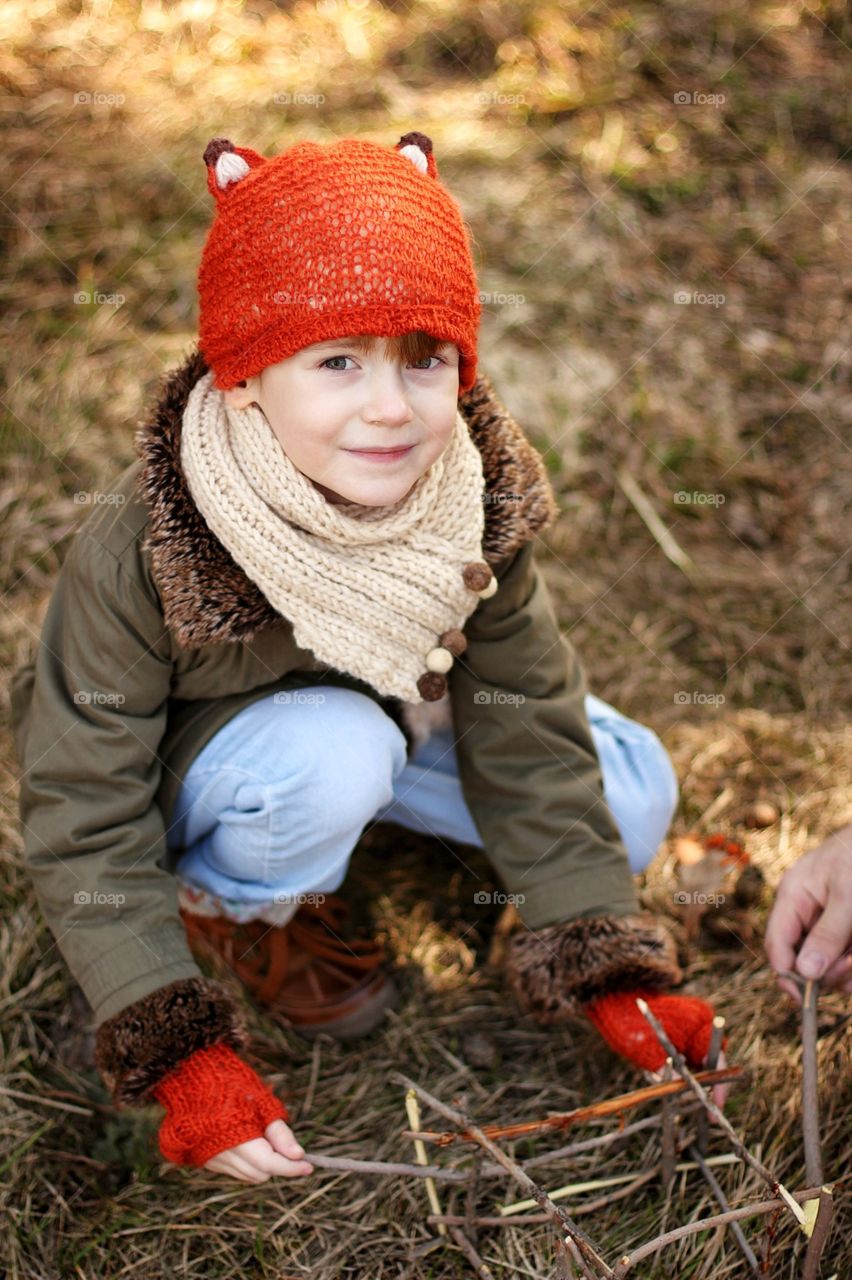 Little girl builds a dad of branches in a park with dad