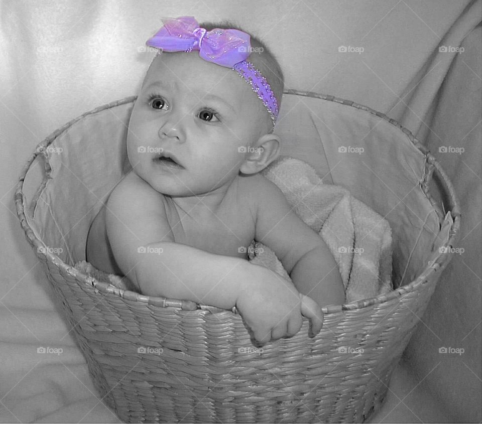 Little Baby, Purple Bow. Sweet baby girl in a basket, wearing a purple bow. 