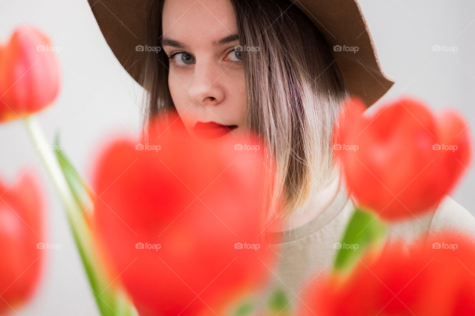 Woman’s portrait through red tulips bouquet 