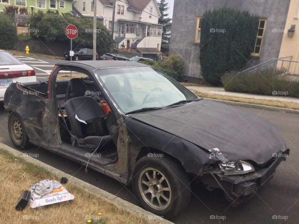 A destroyed car with the doors and trunk missing 
