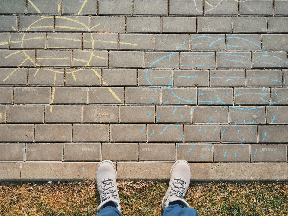 Person's feet and drawing of concrete sky on bricks