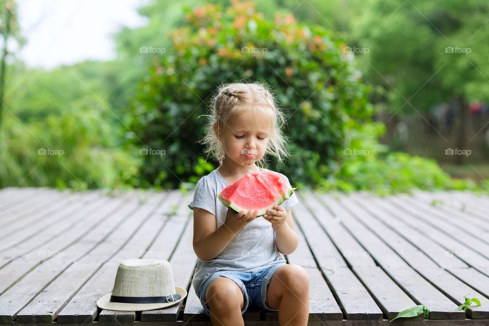 Cute little Caucasian girl eating watermelon outside at summer 