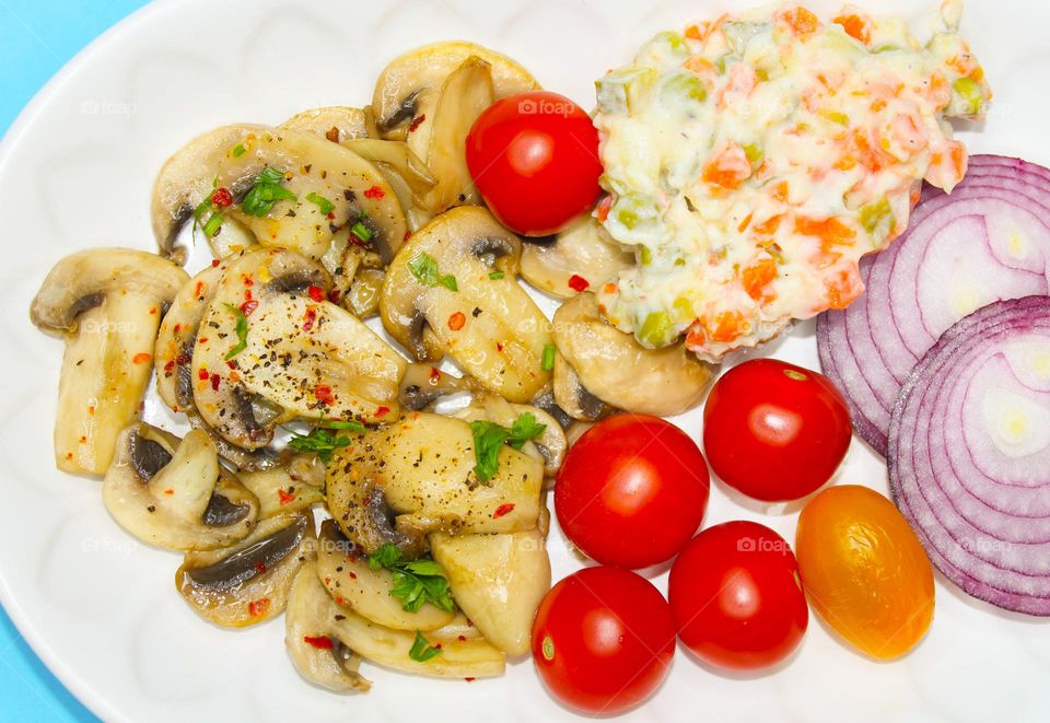 Stewed mushrooms with vegetables on a white plate
