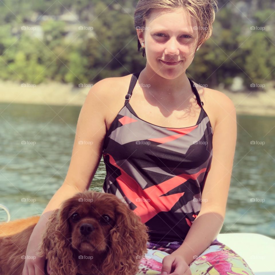 A teenager enjoying the sunshine on a warm summer day on the boat with her trusty canine companion.