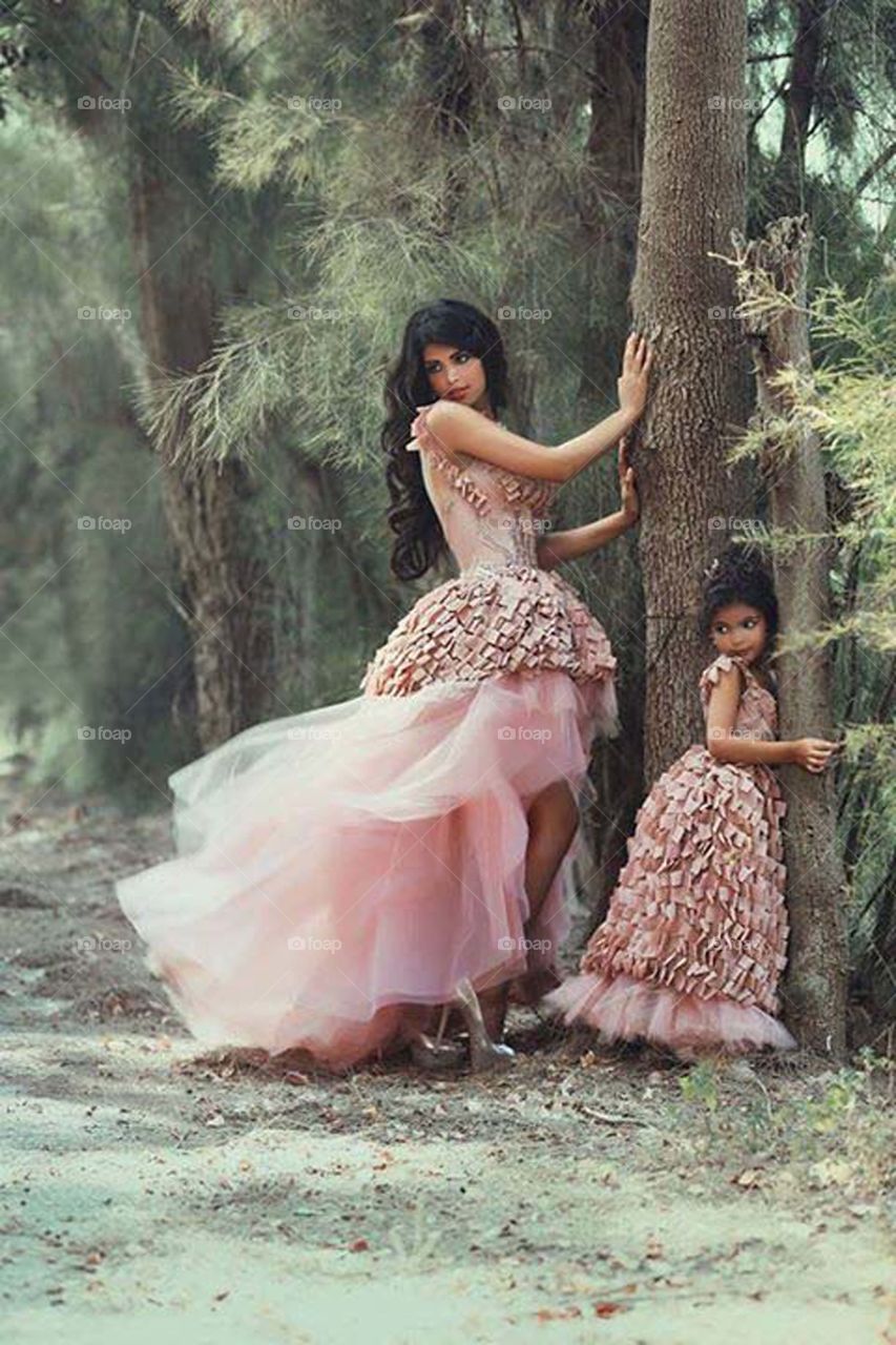 Young woman and cute girl posing near tree