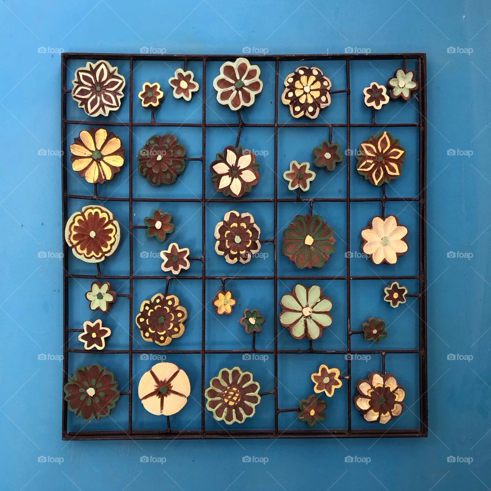 A square frame with twenty five smaller squares surround various circular shapes in blue, yellow, and brown.