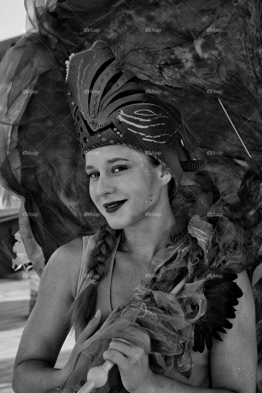 girl with an umbrella in a theater hat and makeup smiling at the camera