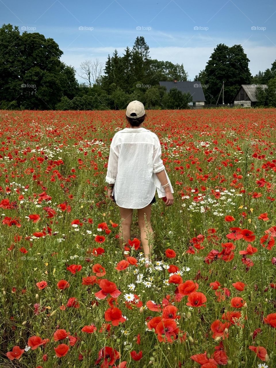 girl in a white shirt walks through a poppy field