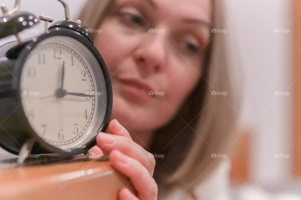 Sad woman with alarm clock 