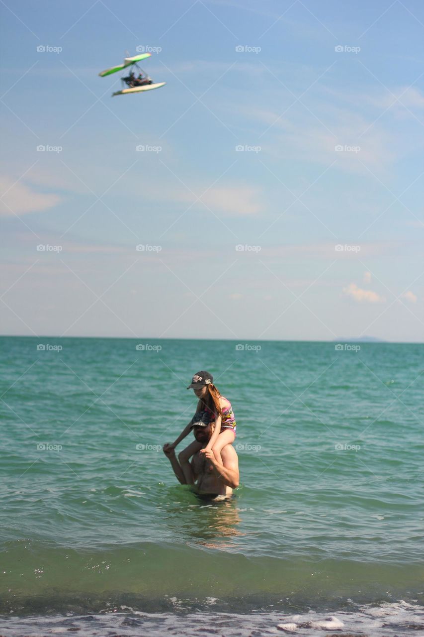 Dad rolls his daughter on his shoulders in the lake