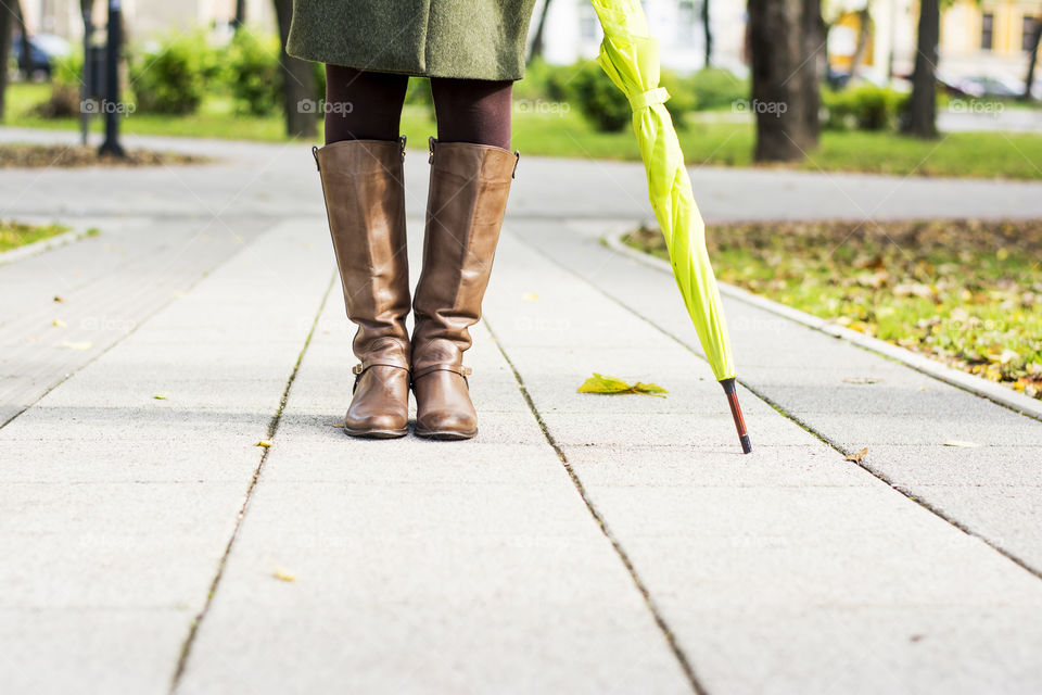 woman in leather boots. woman in leather boots with umbrella standing in a park