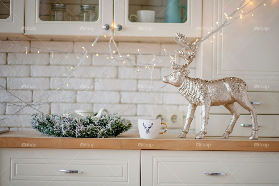 Festive winter cozy kitchen interior with garlands, decorations and gifts.  Christmas dinner at the decorated table.