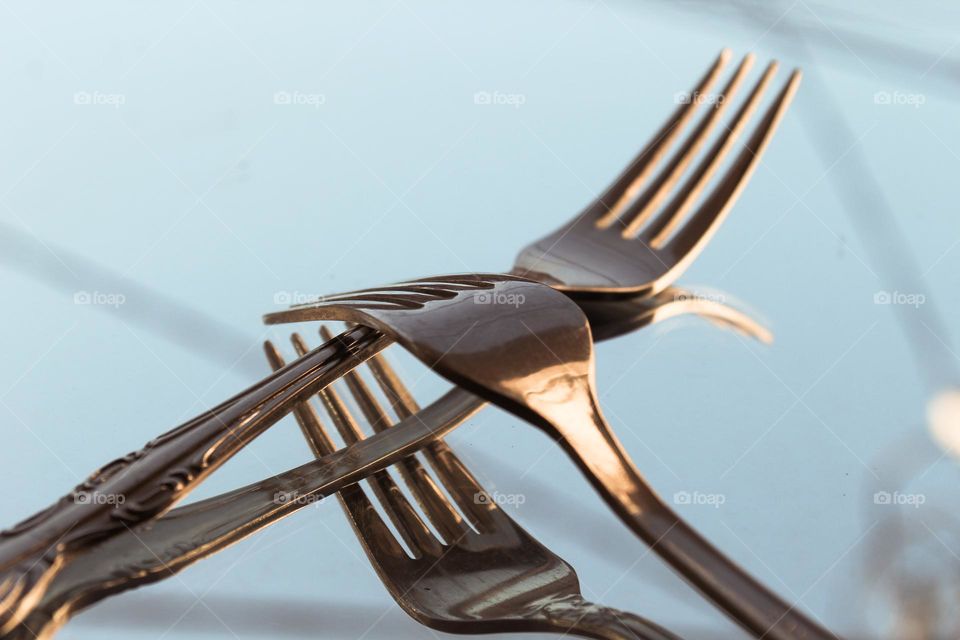 Close up of two metal forks on the mirror.  A forks is cutlery or kitchen tools.