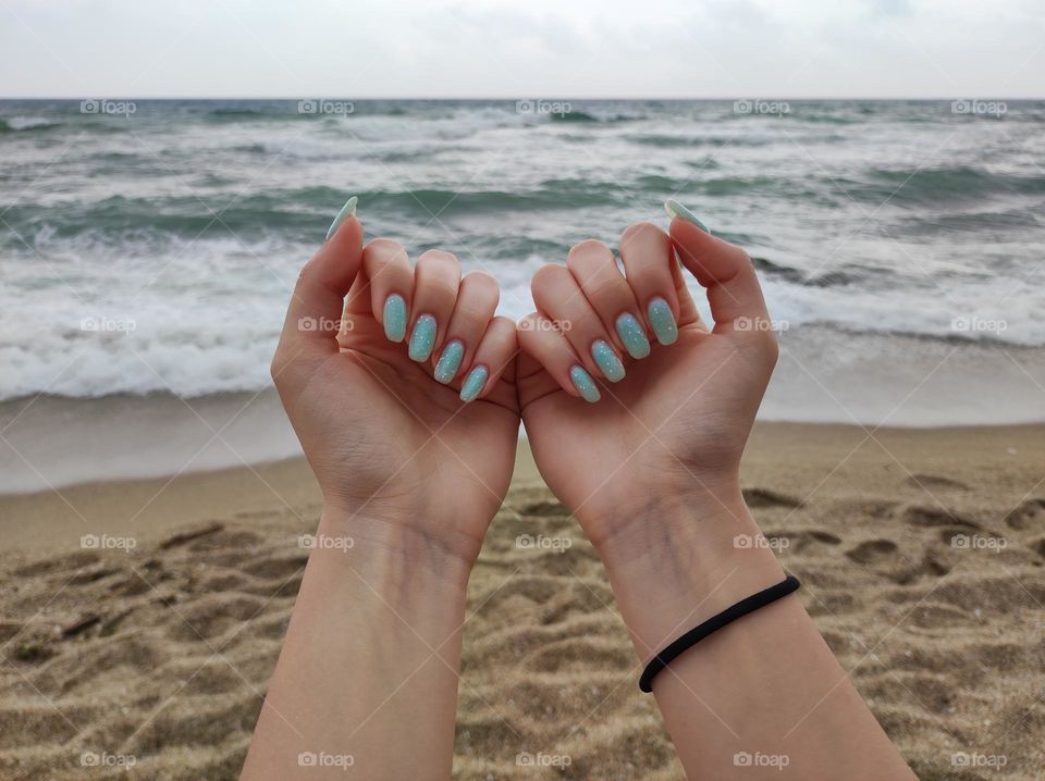 Gel nail manicure with blue-green base/ Beautiful polish on nails/ Naturally long nails with gel nail polish/Nails photographed at the seaside /Nails in the nature