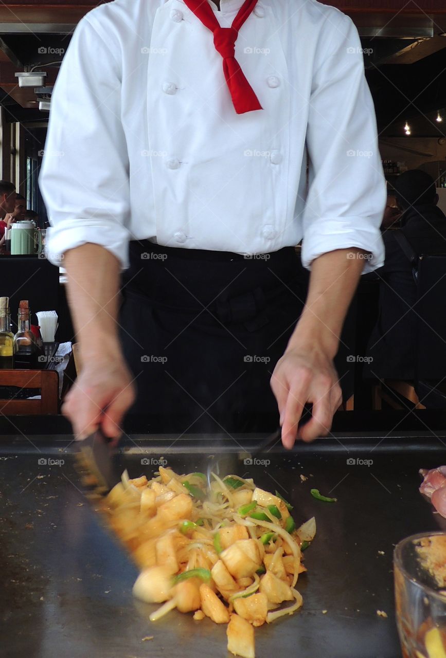 Chef in action. Chef preparing food at steam table in front of guest