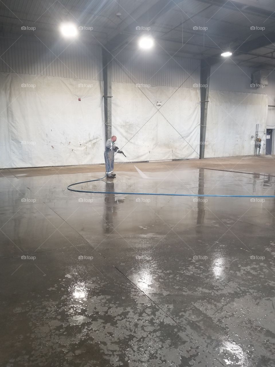 person cleaning a floor with a pressure washer