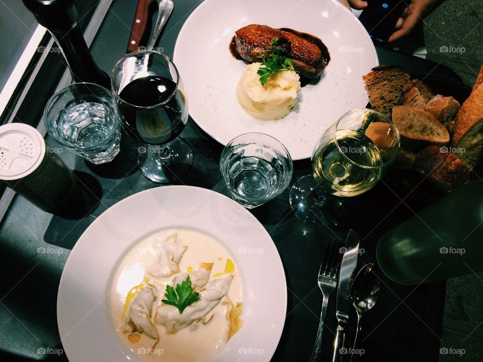 Food photo in Paris France of duck breast with potatoes and pasta with foie gras and truffle. With wine & bread.