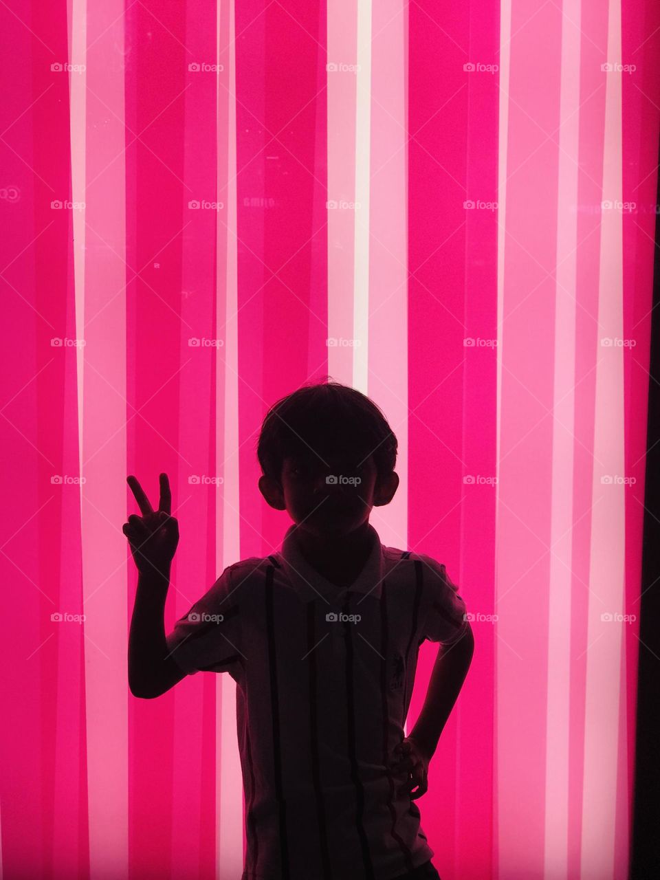 Magenta background and boy showing victory symbol 
