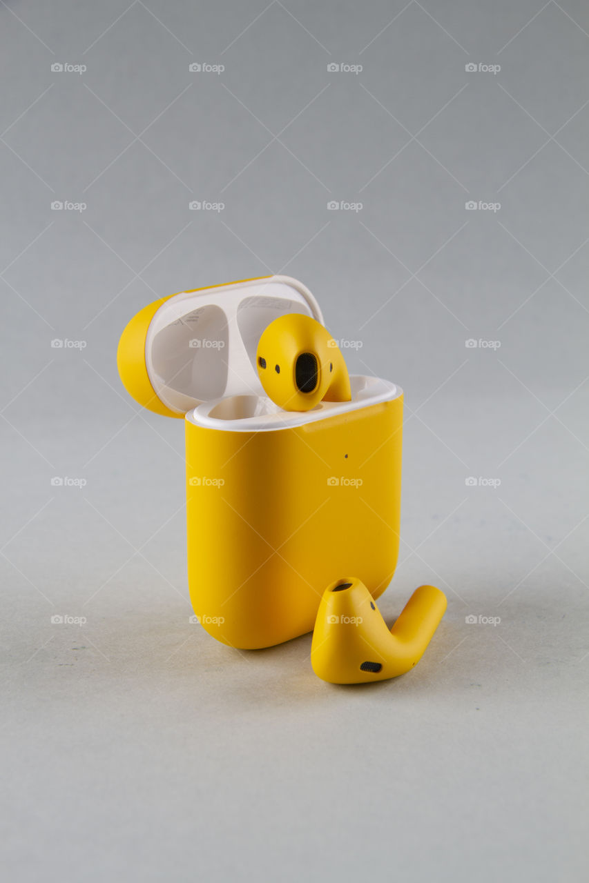 Yellow colour airpods with white background.