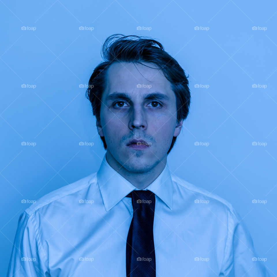 Man in office white shirt and tie looks like American Psycho, blue light