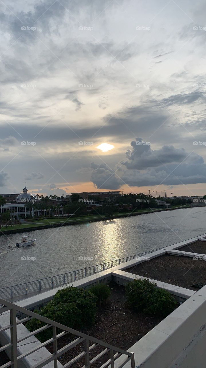 Gloomy, yet relaxing shot of a river nearby. With a sunset in between gray clouds, and that one boat in the water, this photo is sure to give off an independent yet comforting feel.