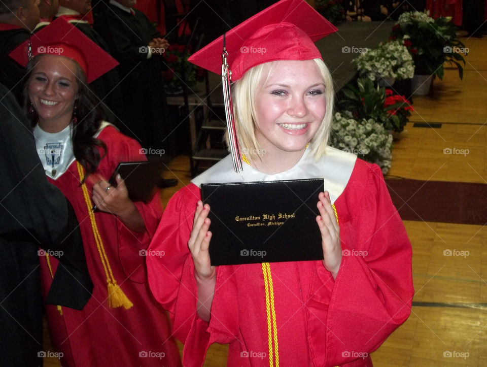 Portrait of a happy student with graduation cap holding certificate in hand