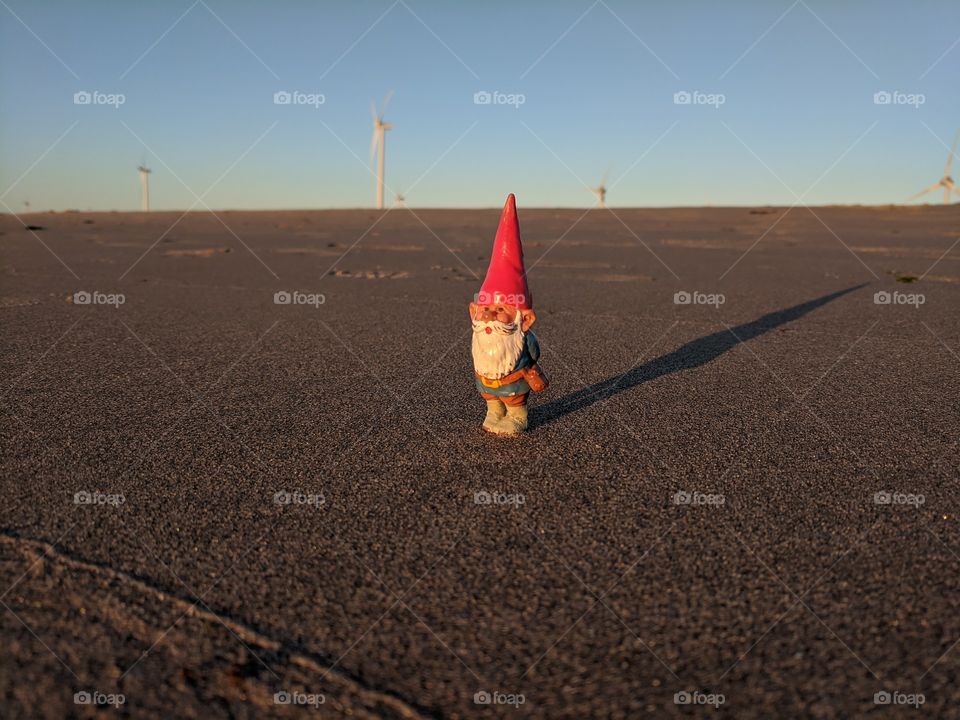 Lonely gnome enjoying the view at beach during the golden hour