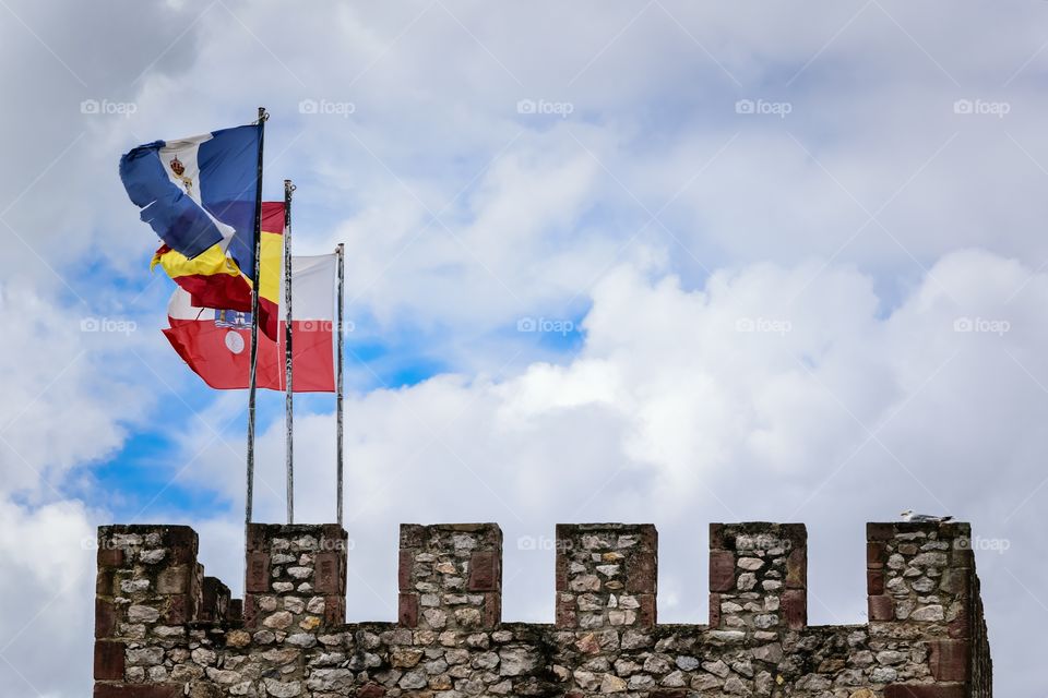 Flags of San Vicente de la Barquera, Cantabria and Spain flying in the wind.