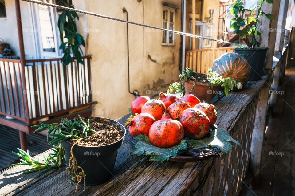 Pomegranate on the plate on the outdoor terrace on a sunny day. Still life from pomegranates. Typical house in Tbilisi, Georgia