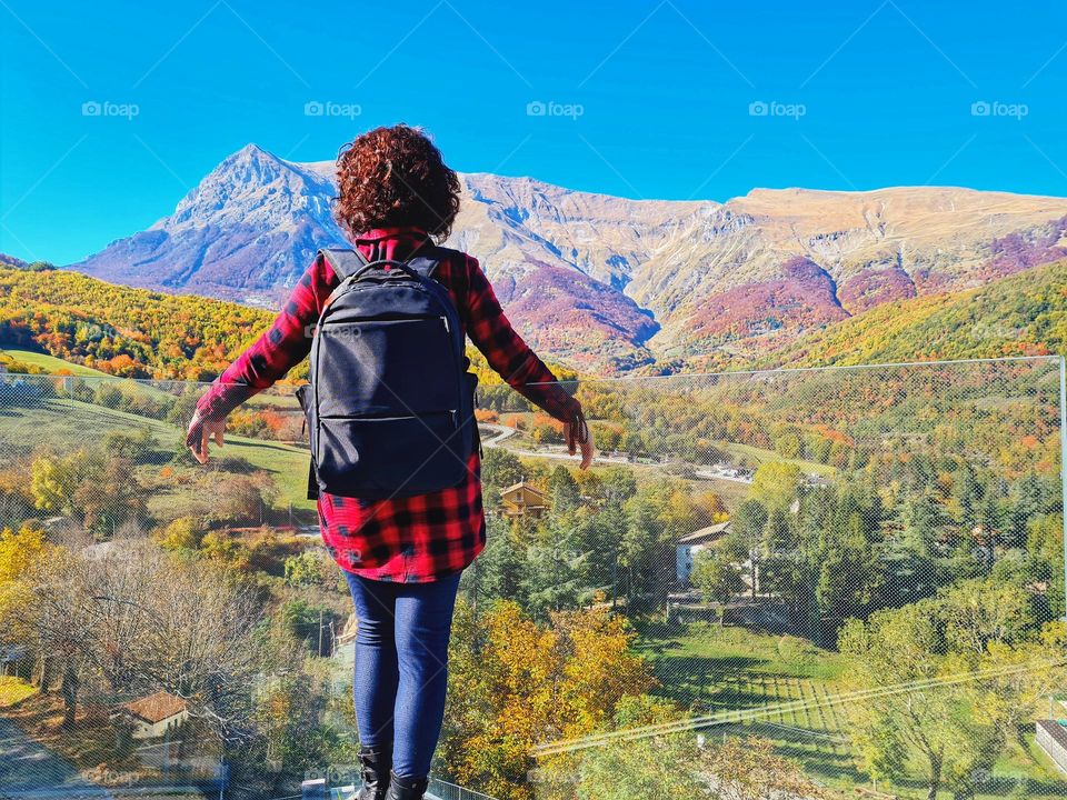 woman hiker from behind looks at the splendid Mount Vettore