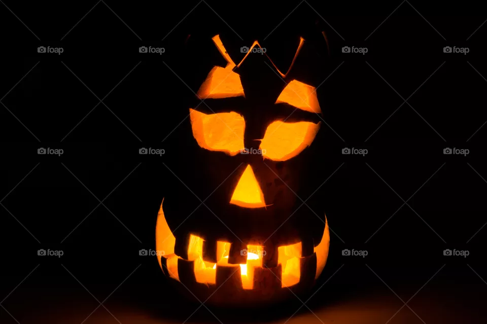 Evil pumpkin face for Halloween in a dark room at night close-up.
