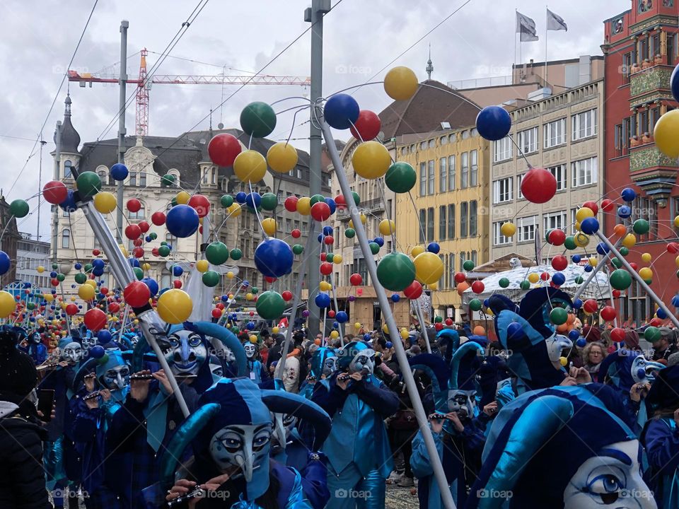 a large crowd of people running in the city among large buildings. a crowd of people in masquerade costumes and masks at a fundamental festival in Switzerland. people in bright costumes on a holiday
