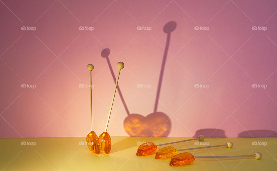 Lollipop candy with shadows on the yellow-pink background 